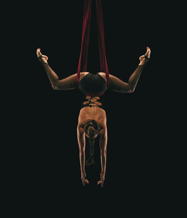 Woman in a graceful yoga pose against a dark background with sunflare accents.